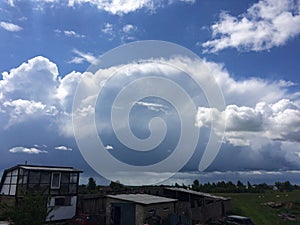 the landscape of a Russian village in summer with colorful houses and a blue sky with huge white clouds