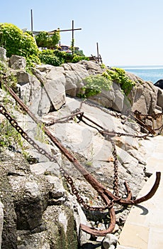 Landscape with a rusty anchor, chains, rocks, green bushes in the city of Sozopol, Bulgaria