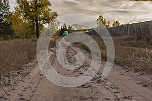 Landscape with sandy road leading to small green-yellow colored house