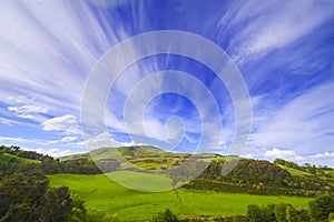 Landscape scenery of green valley with trees, hill and cloudy sky