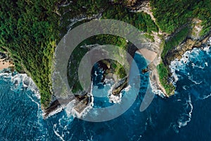 Landscape with scenic rocks and blue ocean with waves in Indonesia. Aerial drone view