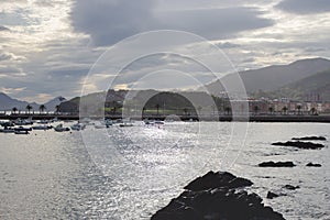 Landscape from the sea of town in Basque country, Spain. Picturesque seascape with mountains and boats in bay.