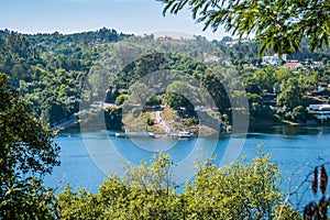 Blurred tree leaves overlooking the river ZÃÂªzere with the structure of the fluvial beach next to Cabril dam, PedrogÃÂ£o Grande PT photo