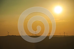 Landscape and several wind turbines silhouettes on sunset