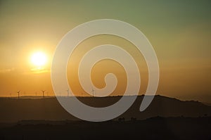 Landscape and several wind turbines silhouettes on sunset