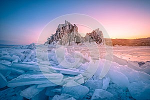 Landscape of Shamanka rock at sunrise with natural breaking ice in frozen water on Lake Baikal, Siberia, Russia