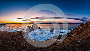 Landscape of Shamanka rock at sunset with natural breaking ice in frozen water on Lake Baikal, Siberia, Russia