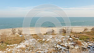 Landscape on the shore of the sea with snow and blue sky.