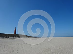 Landscape shot of the coast and the red Texel Lighthouse in De Cocksdorp, Netherlands