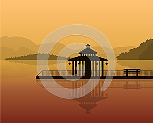 Landscape - silhouette of a house on a background of mountains, sky with reflection in water.