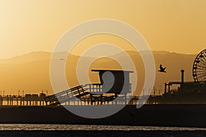 Landscape of the silhouettes of a Ferris Wheel and a pier on the Santa Monica State Beach, the USA