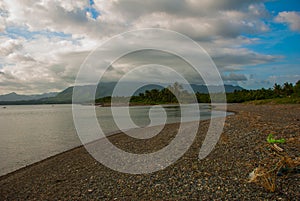 Landscape sky with clouds, volcanic sand on the beach. Pandan, Panay, Philippines.