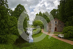 Landscape with small wooden bridge and a stone barn in Mikhaylovskoye in Pskov Region, Russia