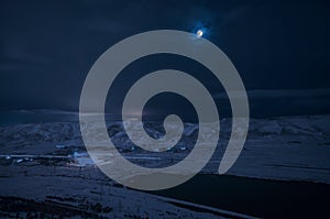 Landscape of snowy mountains and lake with full moon above. The moon and clouds on sky. Baku, Azerbaijan, Xojasan Lake