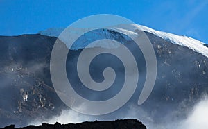 Landscape of a snowy peak of Mount Kilimanjaro covered with clouds under sunlight and shadow