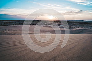 Landscape of sun over skyline in desert at White Sand Dunes Mui Ne, Vietnam. Countryside panorama under scenic colorful sky at