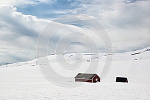 Landscape at sunny summer day with snow and lonely houses, on the road Aurlandsfjellet, Norway