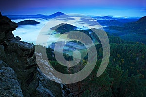 Landscape before sunrise. Cold misty foggy morning in a fall valley of Bohemian Switzerland park. Hills with fog, landscape of