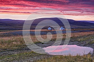 Landscape at sunrise with sky reflected in a large puddle