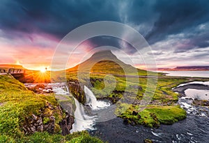 Landscape of sunset over Kirkjufell mountain with Kirkjufellsfoss waterfall and colorful pileus cloud on summer at Iceland