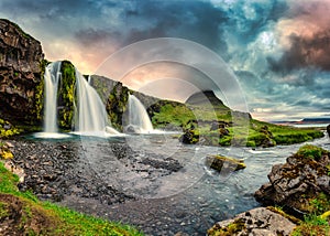 Landscape of sunset over Kirkjufell mountain with Kirkjufellsfoss waterfall and colorful pileus cloud on summer at Iceland