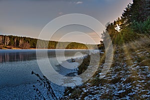 landscape sunset in the woods. winter pine forest on the banks of the frozen river