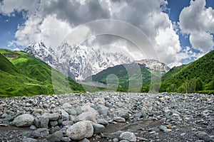 Landscape of svaneti mountains, Georgia. Amazing view of mountain Dzhangi-Tau and glacier Khalde from stones shore of river