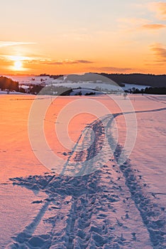 Landscape with trail on snow at sunset