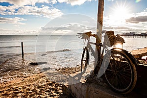 The landscape of the tranquil sea coast in the evening sun, in the foreground of an old bicycle.