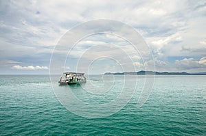 Landscape with turquoise tropical sea, cargo ferry, scenic clouds and tropical Koh Chang island on horizon in Thailand