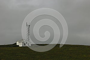 landscape with two houses near electric tower under cloudy sky