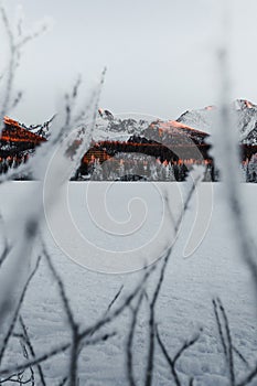 Landscape vertical photo of frozen and snow covered Strba tarn Strbske pleso in winter time. Mountains in Slovakia with frozen