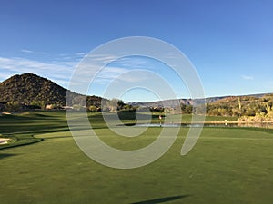 Landscape view of the 18th hole of a golf course with mountains in the background