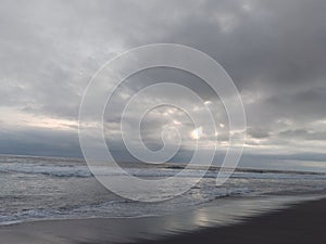 landscape view of black sand beach with dark sky covered with clouds