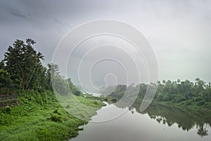 A landscape view of a calm river with green trees and mountain in India