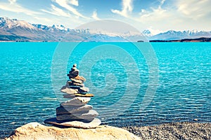 Landscape view of colorful lake Pukaki, stones pyramid and Mt Cook in distance, New Zealand