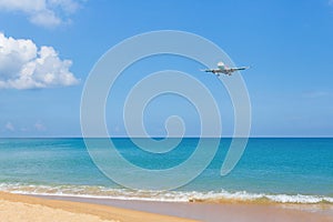 Landscape view contained with blue sky and sea, golden sand while air plane landing on runway near the coast