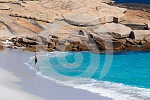 Landscape view of a couple swimming in the clear blue waters of Blue Haven Beach near Esperance in Western Australia under a