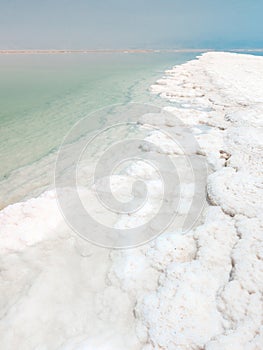 Landscape view on Dead Sea salt crystals formations, clear cyan green water at Ein Bokek beach, Israel