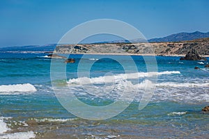 Landscape view of a empty sandy beach with the sea and its waves on a nice summer day with blue sky.