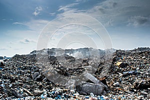 Landscape view at the garbage dump full of smoke, litter, plastic bottles,rubbish and trash at tropical island