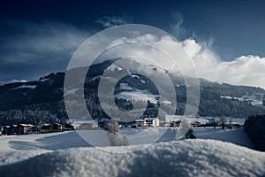 Landscape view of the houses on snow with fir forest trees on the hill