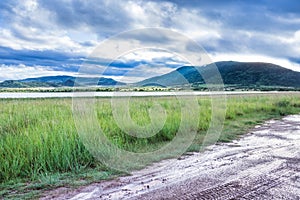 Landscape view of a lake surrounded by mountains and green savanna grassland, Pilanesburg Nature Reserve