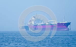 Landscape view of large and heavy rusty cargo container ship on river for transportation of crude oil. International shipment of