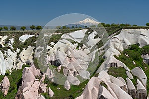 Unique landscape of rock formations and cave houses with mount Erciyes, Goreme national park, Cappadocia Turkey photo