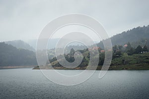 Landscape view of mountain village on Zaovine lake in fogg