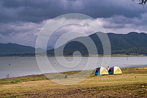 Landscape view of nature Camping tents near river lake with mountain range and dramatic clouds sky background