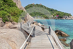 Landscape view of old wooden walkway bridge through the rock at Koh Nang Yuan Island under blue sky in summer day