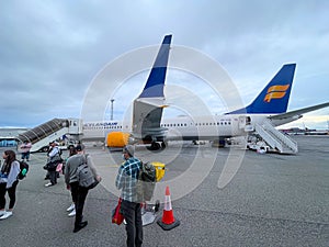 Landscape view of passengers deplaning IcelandairÃ¢â¬â¢s Boeing 737MAX 9 Passenger jet at Leifur