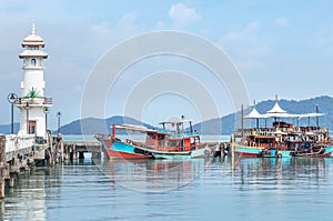 Landscape view of public white lighthouse on pier of Bang Bao fishing village with fishing boats mooring at Koh Chang Island,Trat,
